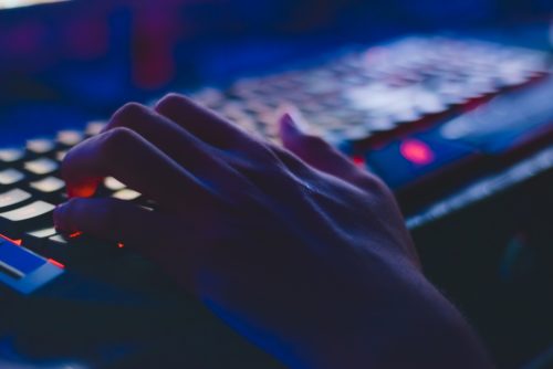 A hand resting on a gaming keyboard - Why online gaming addiction is harmful excessive gaming - The Gamerian Blog