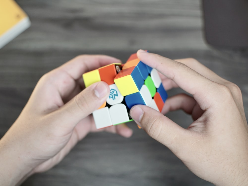 Hands playing with Rubik's cube - How Many People Can Solve A Rubik’s Cube? - thegamerian.com Gaming Blog
