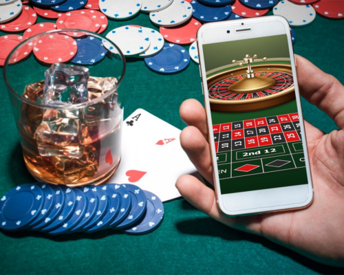 Unknown hand holding a mobile phone showing roulette game - Newest RTG Casinos - The Gamerian thegamerian.com Gaming Blog